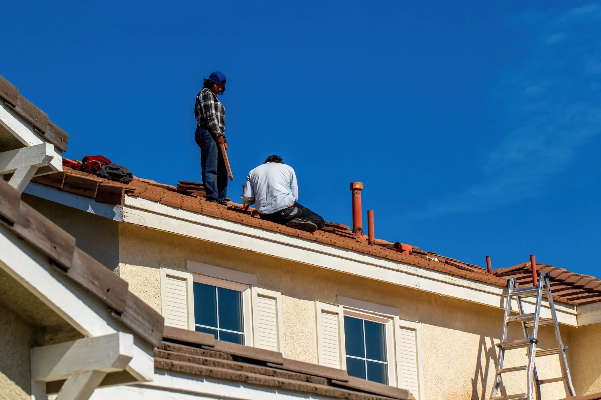 Roofers working along the edge of a residential roof