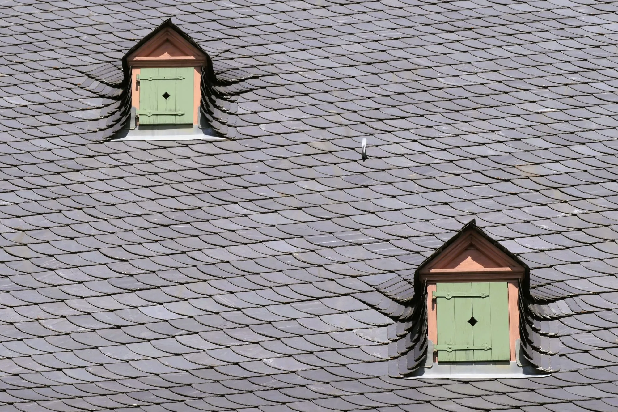 A slate roof with dormer windows against the sky
