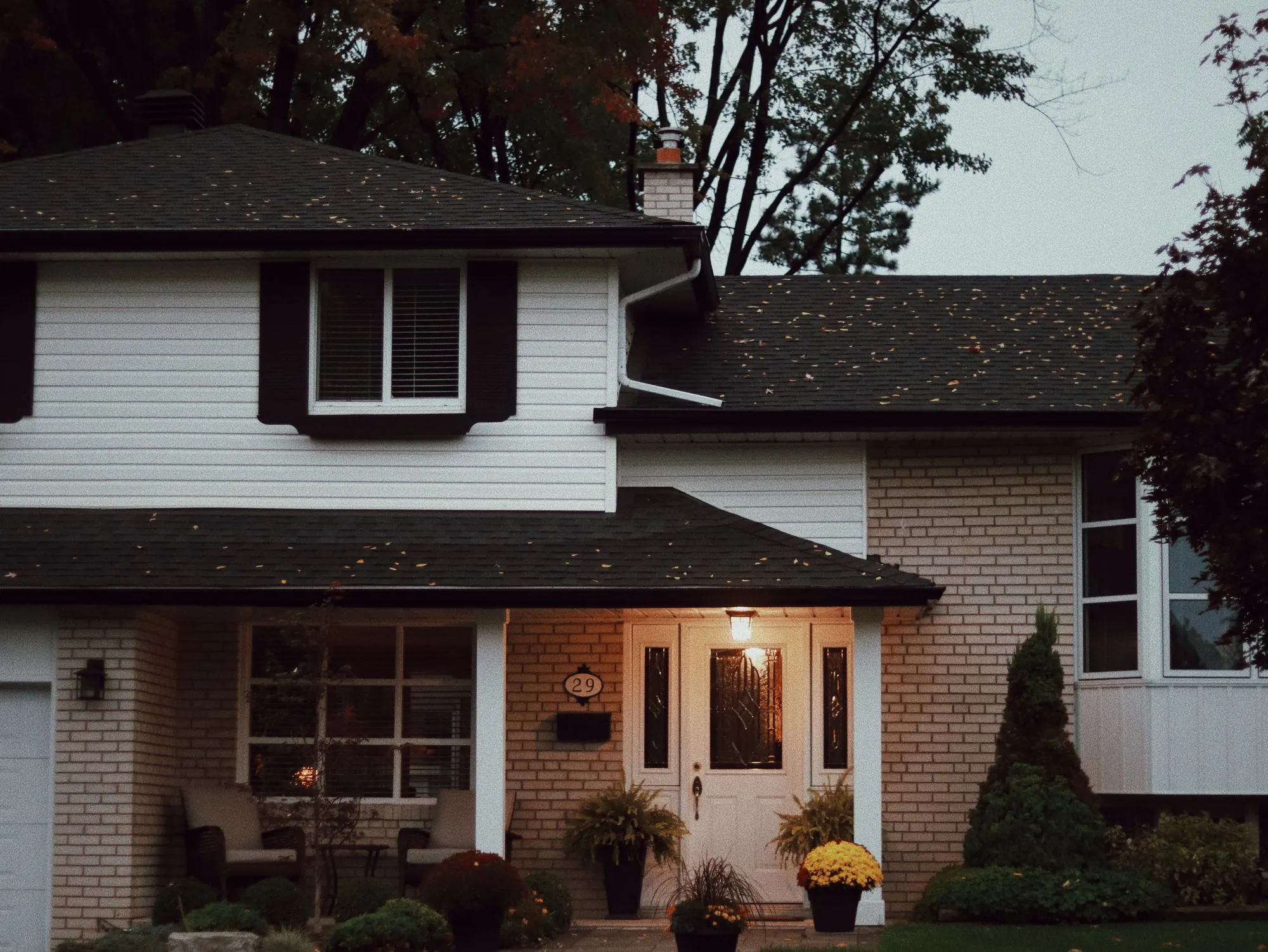 A suburban house with a dark shingle roof and brick front