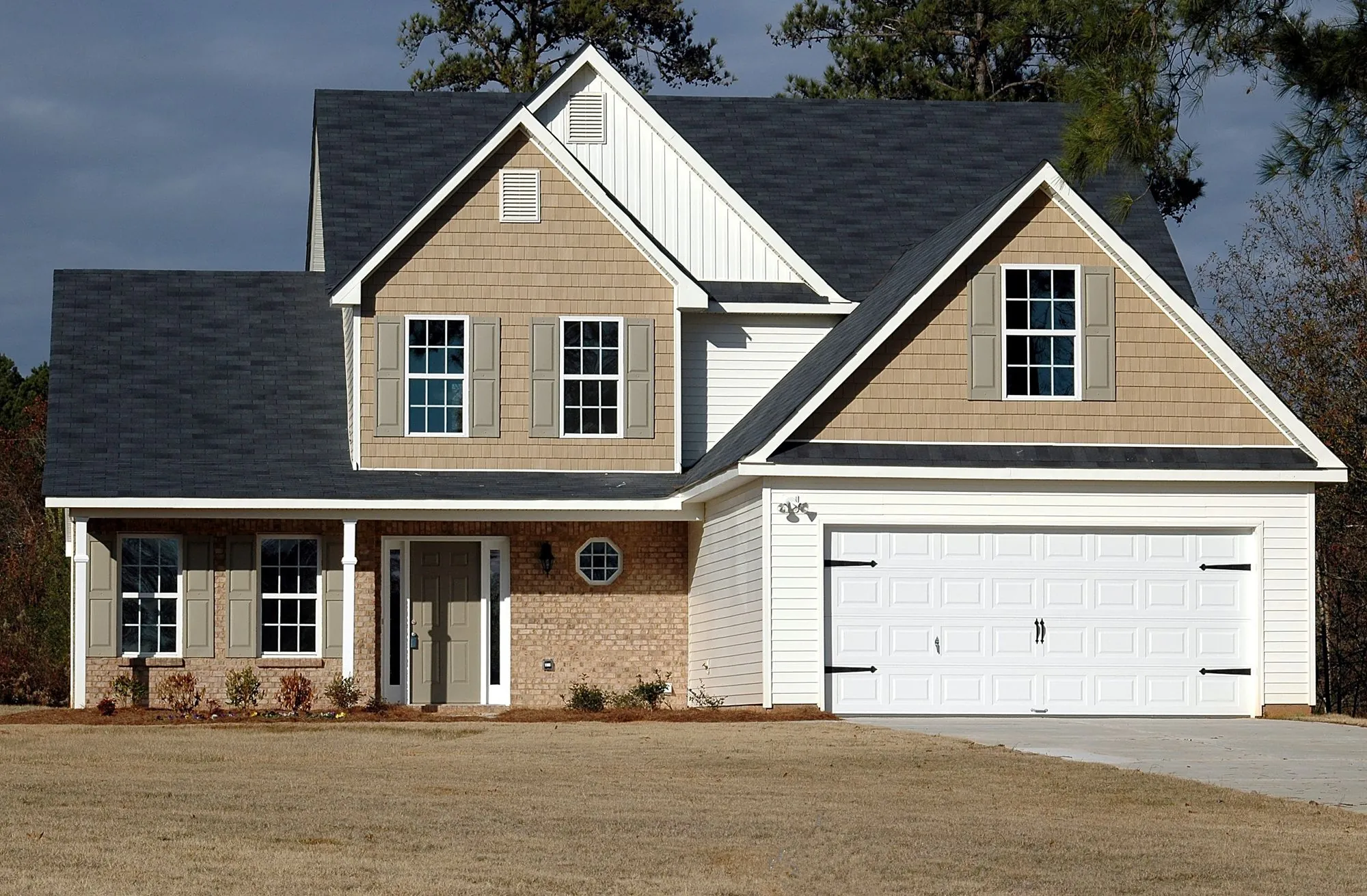 A newly built house with a dark shingle roof and attached garage