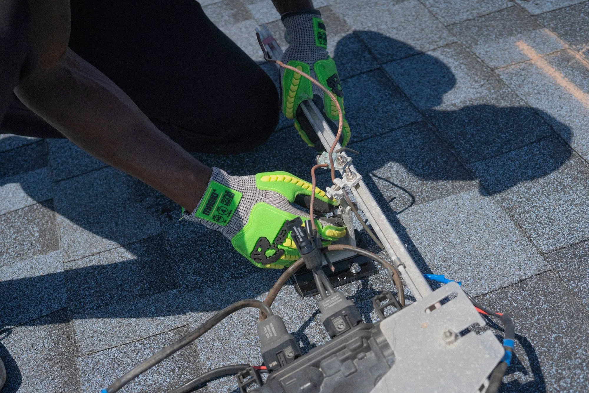 A roofer fixing new shingles down with a nail gun