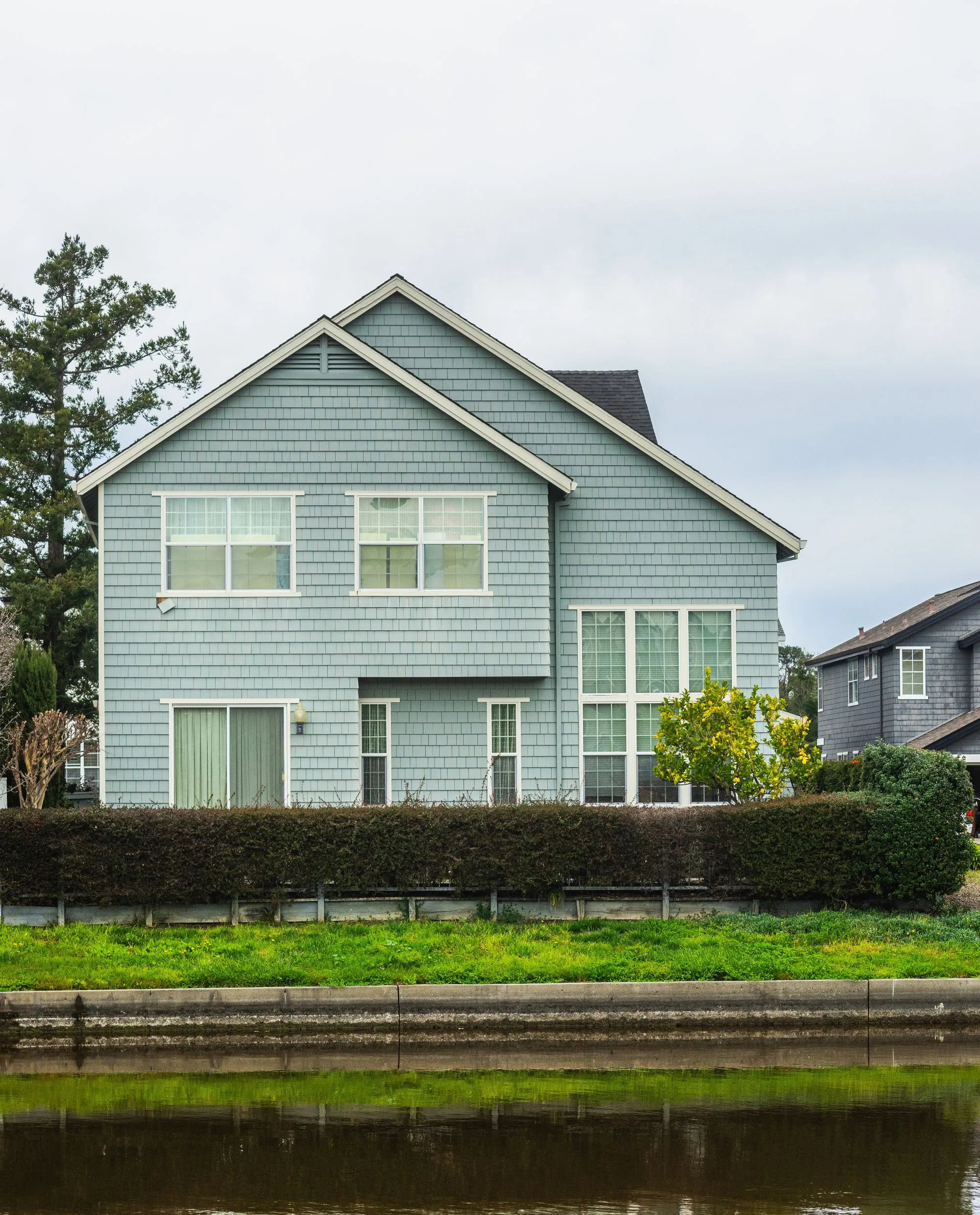 A two-storey house clad in pale shingle siding